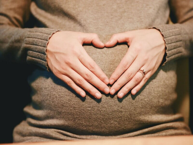 Babybauch mit Händen als Herz